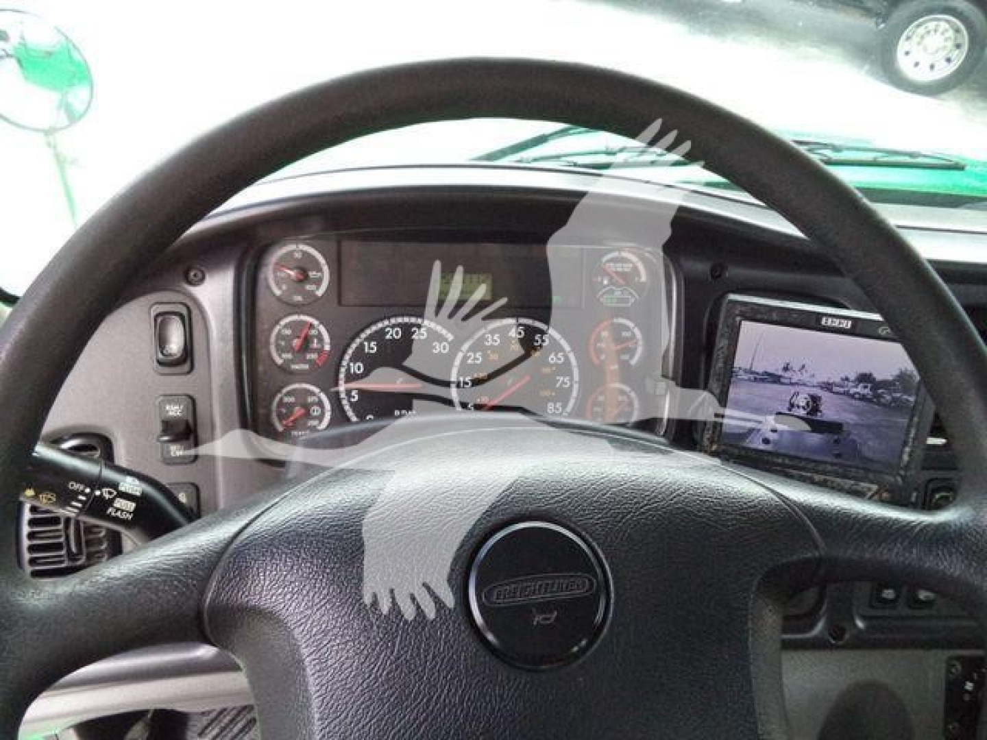 Dashboard view of 2015 Freightliner M2 106 cab with steering wheel, instrument cluster, and side monitor display.