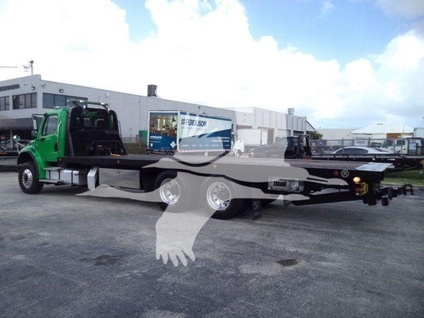 Flatbed tow truck chassis on a green Freightliner M2 106 with extended rollback bed and dual rear axles.