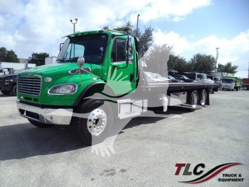 Green Freightliner M2 106 rollback tow truck side view showing cab and flatbed.