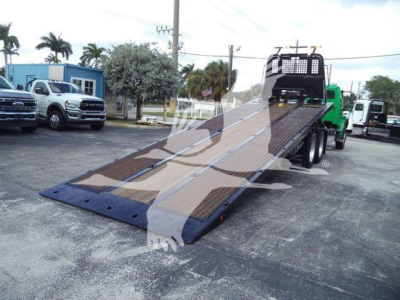2015 Freightliner M2 106 rollback truck with tilted flatbed in service showing loading ramp and rear cab area.