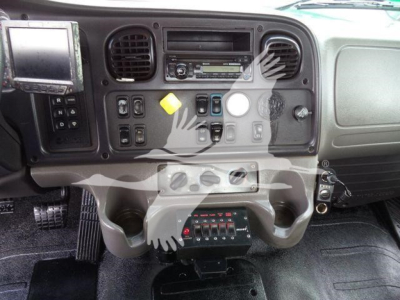 Dashboard of a Freightliner M2 106 cab showing radio, climate vents, control switches and pedal area.