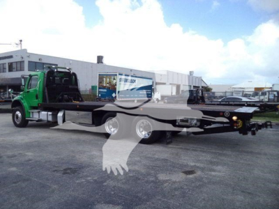 Flatbed tow truck chassis on a green Freightliner M2 106 with extended rollback bed and dual rear axles.