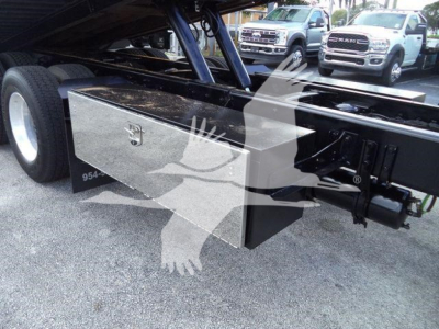 Flatbed area of a 2015 Freightliner M2 106 rollback truck showing a diamond-plate toolbox mounted underframe with hydraulic components and rear axles visible.
