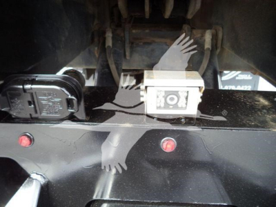 Freightliner M2 106 rollback hitch area showing electrical connector and square power outlet on black metal surface with red reflectors.