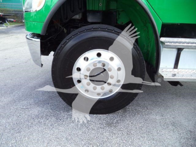 Truck wheel and front fender of a 2015 Freightliner M2 106 rollback showing front wheel and green body panel.