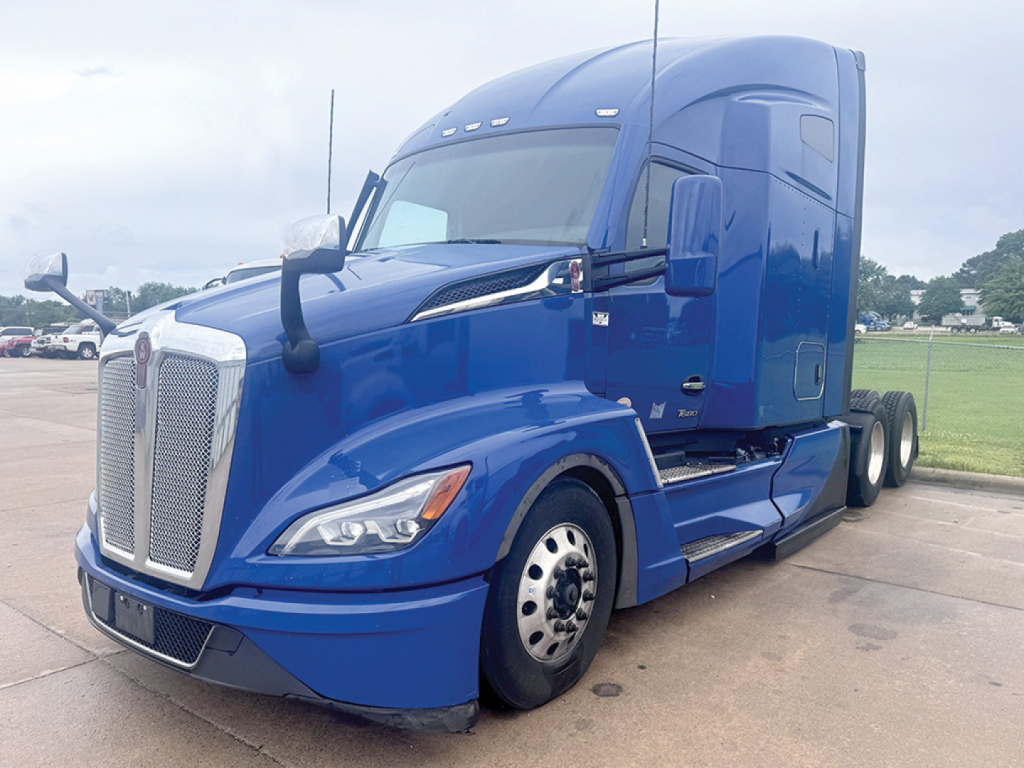 Kenworth T680 Next Gen tractor cab and front wheel showing blue paint and chrome grille