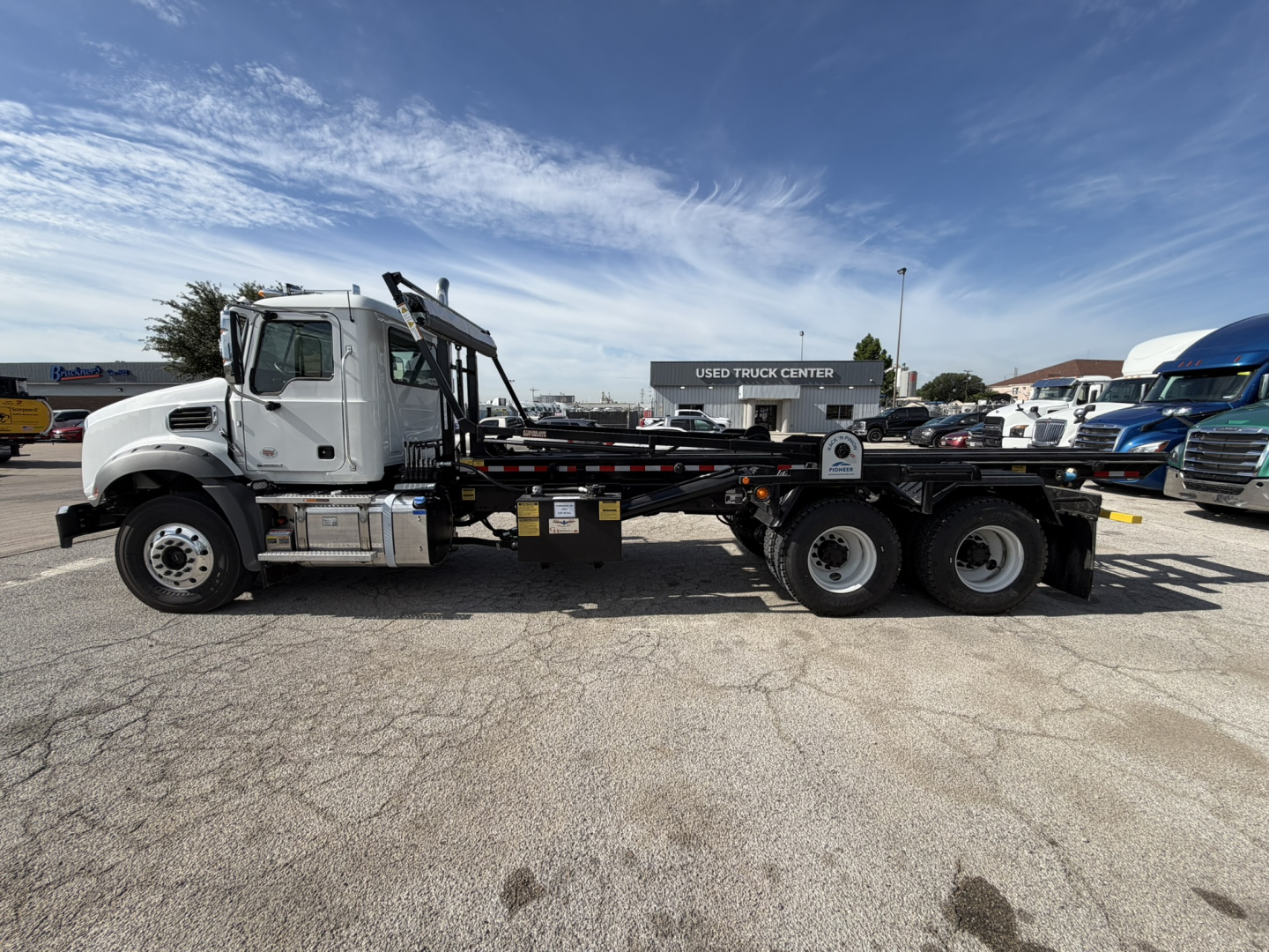 Mack GR64B sleeper cab with flatbed/dump bed and dual rear axles in a dealership lot.