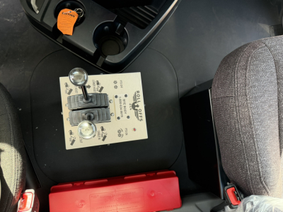 Control panel with two levers and labeled switches in Mack GR64B roll-off truck cab showing gear levers and dash labels.