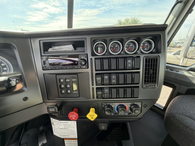 Truck dashboard of a 2026 Mack GR64B showing steering wheel area, gauges, switches, and control panels.