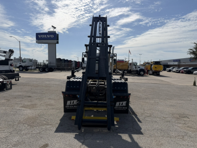 Mack GR64B truck in service bay showing front view with high-reach forklift attachment and surrounding lot.