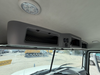 Inside cab of a 2026 Mack GR64B roll-off truck showing the overhead console with storage compartment and control panel, sunroof/awning area, and windshield view.
