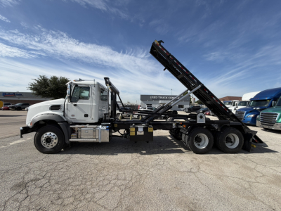 Mack GR64B roll-off truck side view showing hydraulic bed and chassis with black conveyor/hoist system.