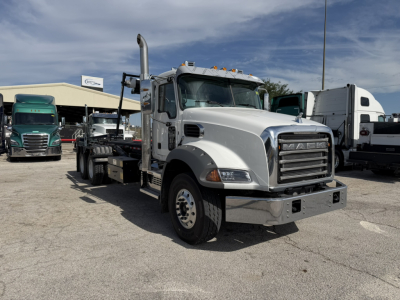 Mack GR64B truck in a lot showing front and side, with chrome bumper and exhaust stack, new condition.