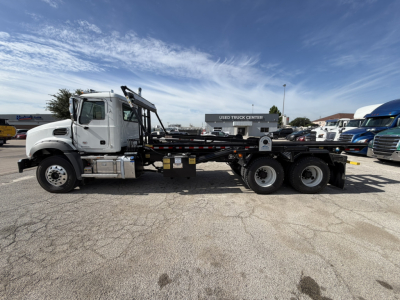 Mack GR64B sleeper cab with flatbed/dump bed and dual rear axles in a dealership lot.