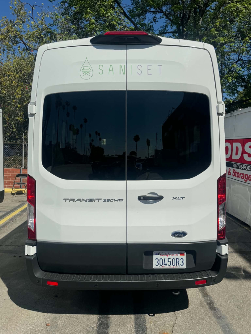 Ford Transit 350 HD rear view showing cargo doors, badges TRAN SIT 350 HD and XLT, California license plate 30450R3, Saniset logo on rear window.