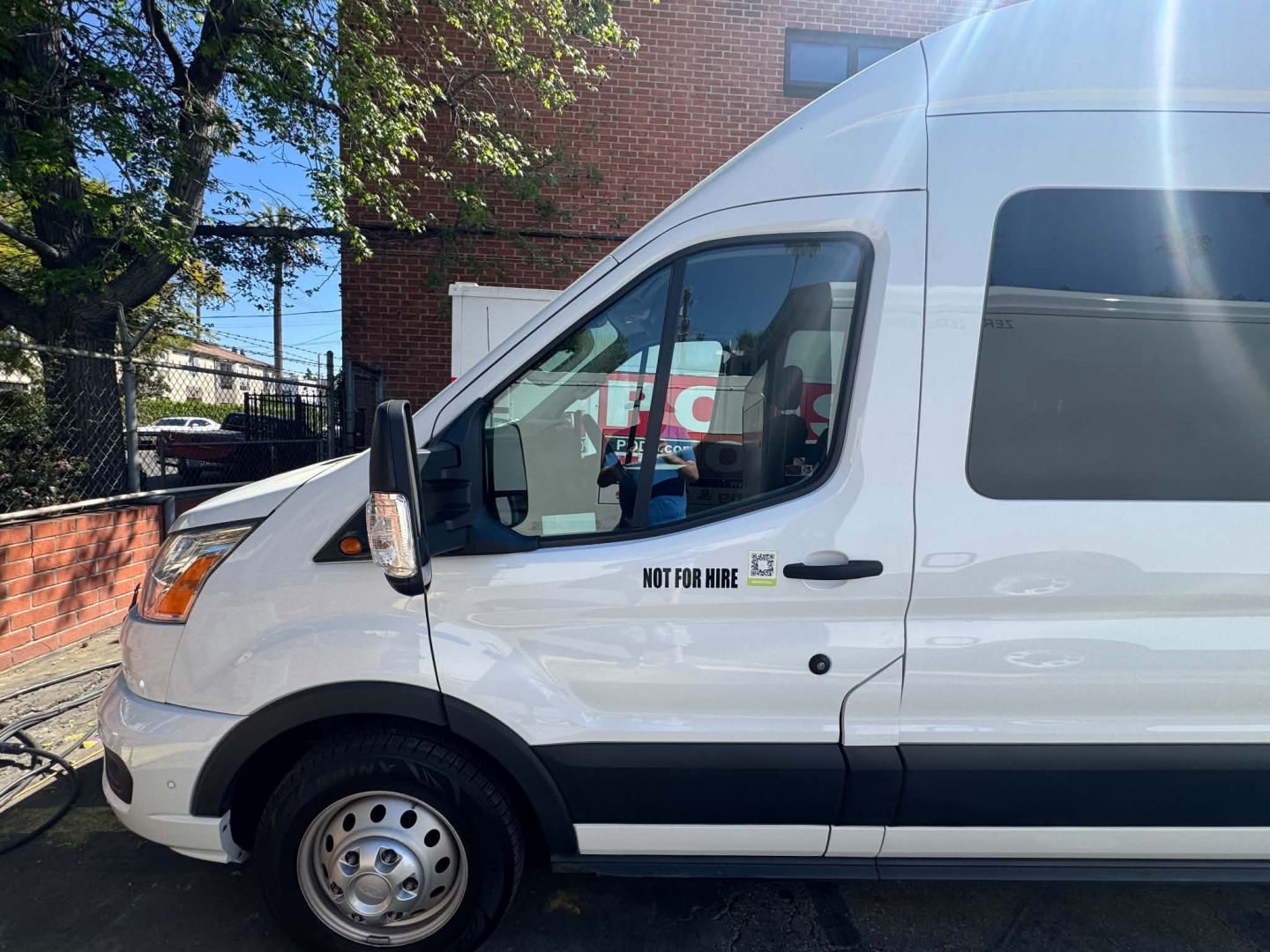 Ford Transit 350 HD side view showing front cabin area with Not For Hire decal and window. Vehicle is white cargo/passenger van.
