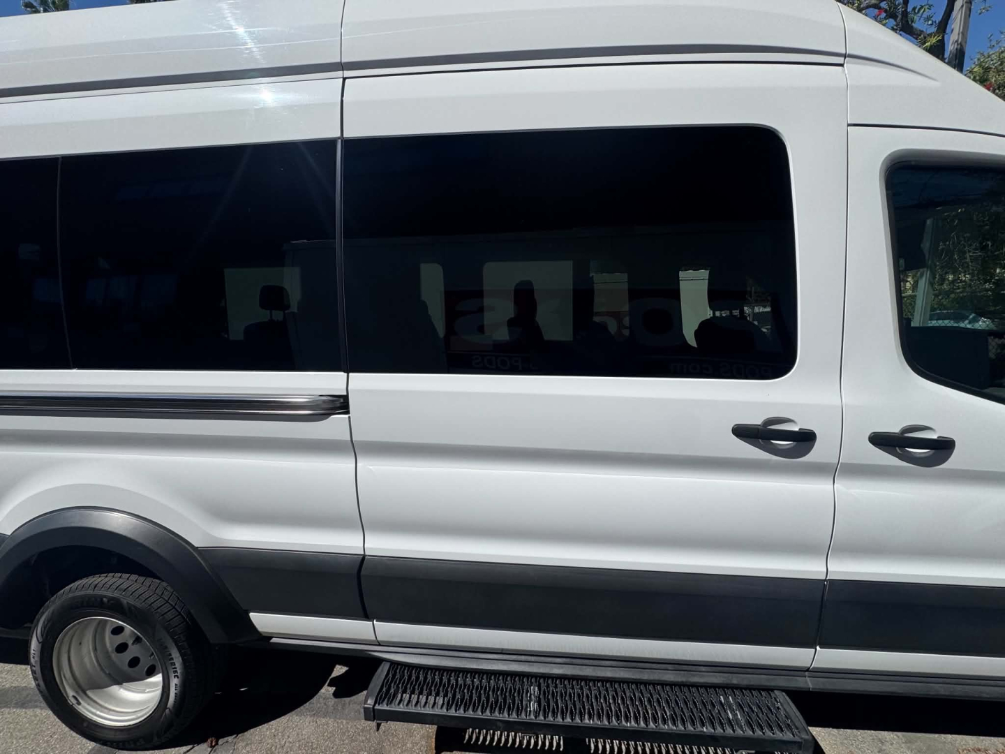 Ford Transit 350 HD passenger van side view showing sliding window and side steps.