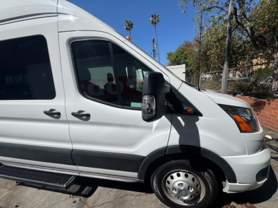 Ford Transit 350 HD passenger van side profile showing front cab and early 2020s styling with side mirror, window, and running board.