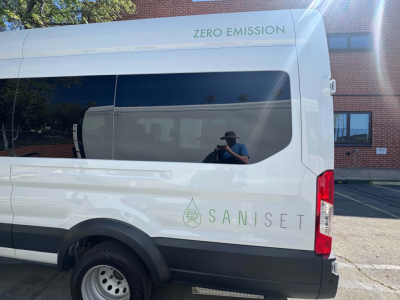 Ford Transit 350 HD passenger van rear side view showing zero emission and Sanisjet branding on white body.