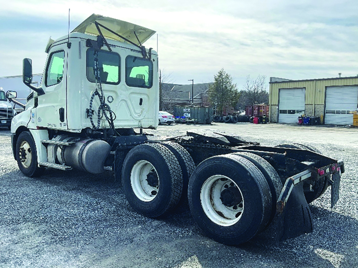 Truck chassis and cab of a 2018 Freightliner Cascadia126 Daycab seen from rear-left, showing tractor frame with three rear axles and dual tires, white cab, VIN and stock info not visible on image