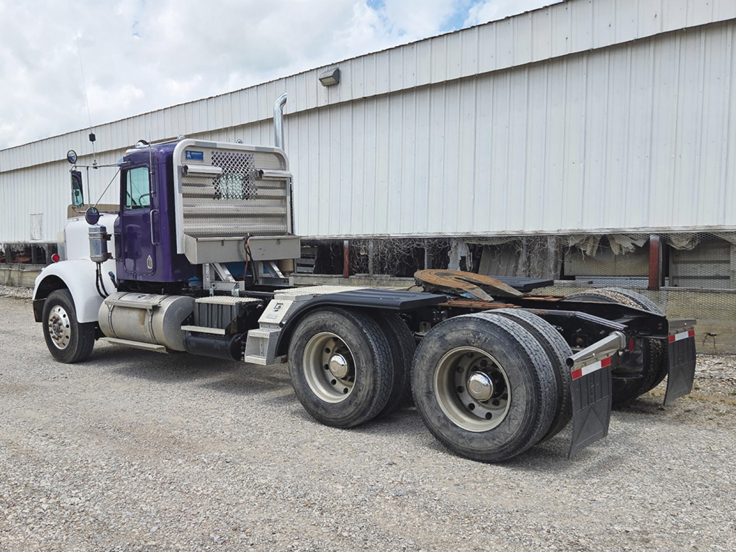 Kenworth W-900A cab tractor with purple and white color scheme, dual rear axles, fuel tanks, exhaust stacks; no visible text on side panels.