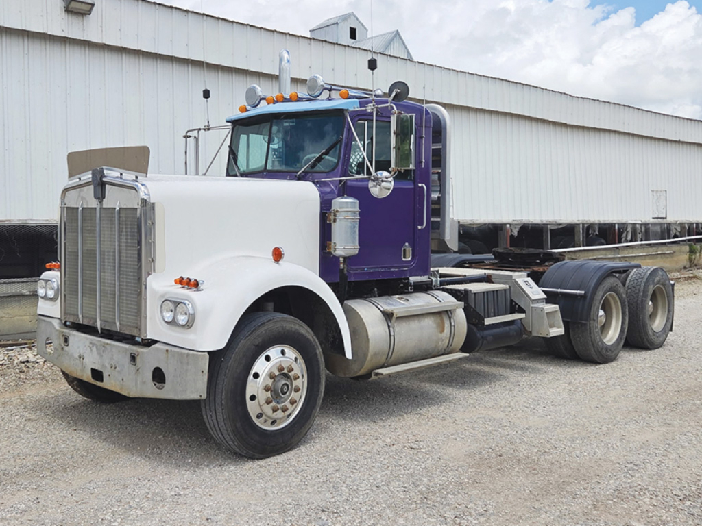 Truck cab and chassis of a 1978 Kenworth W-900A conventional daycab with purple and white color scheme; stock number 551059 visible on placard near front; VIN 161148S is not visible in image.