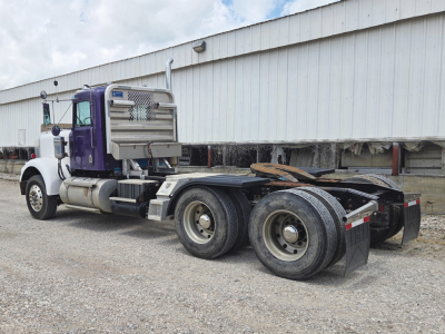 Kenworth W-900A cab tractor with purple and white color scheme, dual rear axles, fuel tanks, exhaust stacks; no visible text on side panels.