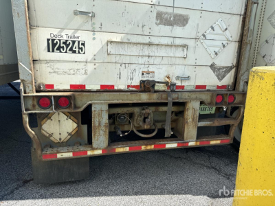 Back of a white Wabash trailer with deck trailer plate 125245, various reflective strips, taillights, and a hitch assembly in the center; some dirt and wear.