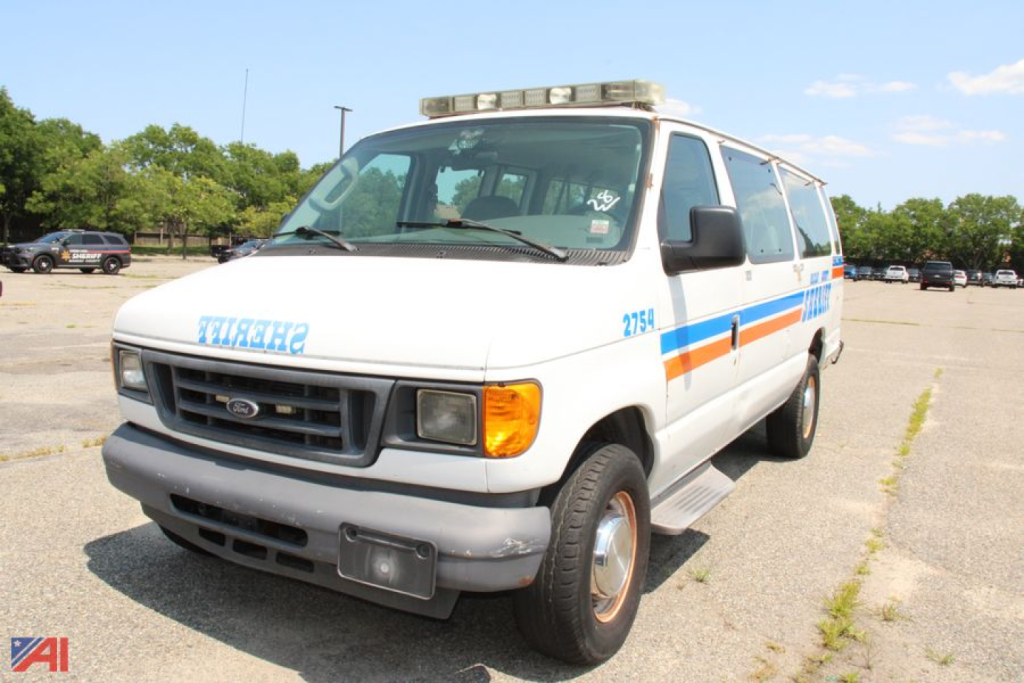 2006 Ford E350 passenger van in service view with light bar on roof and blue side stripe, facing left