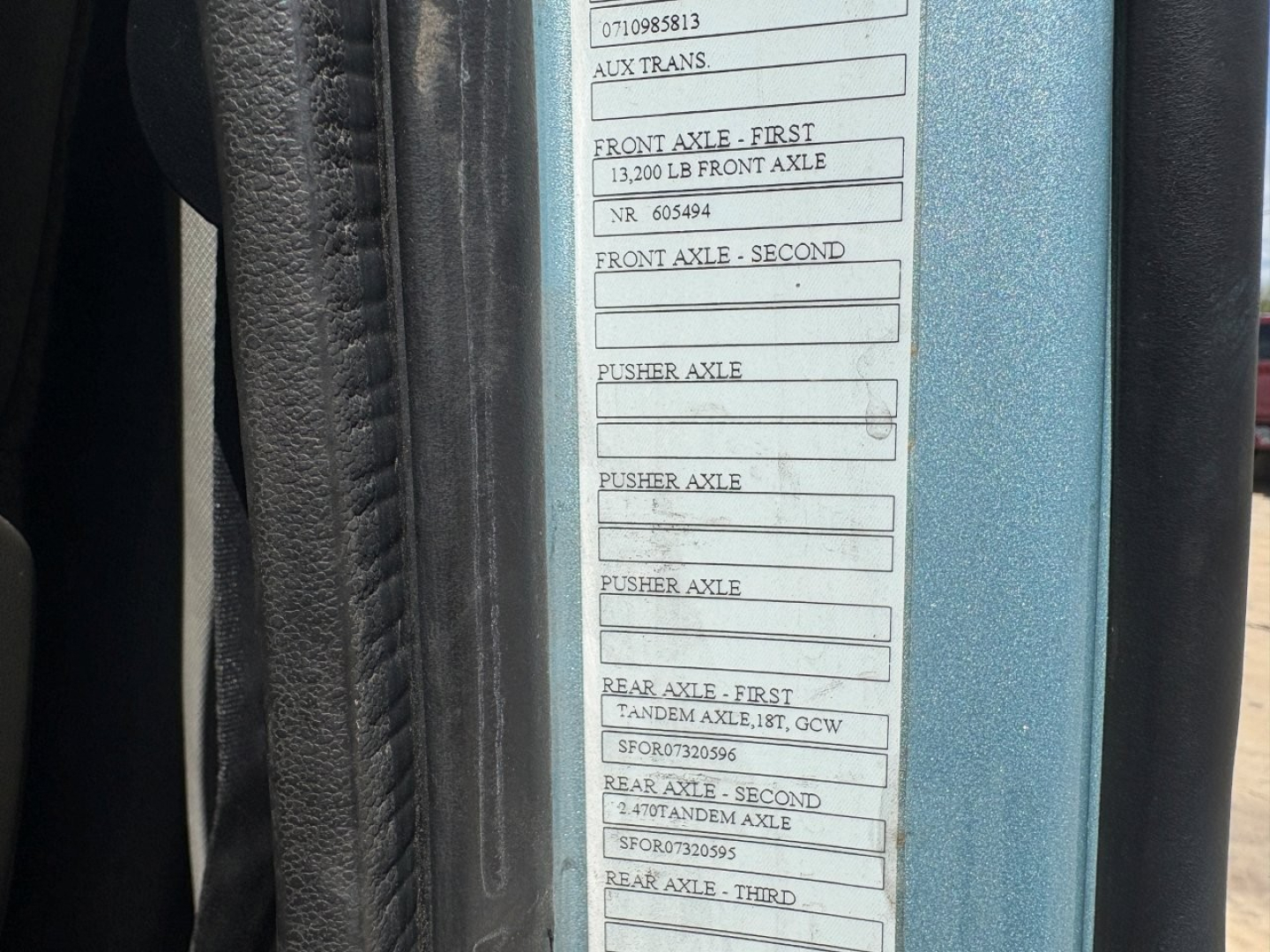 Label plate on Volvo VNL64T760 cab showing axle ratings and serial numbers including 'Front Axle - First 13,200 LB Front Axle' and various 'Pusher Axle' and 'Rear Axle' entries visible on the door jamb.