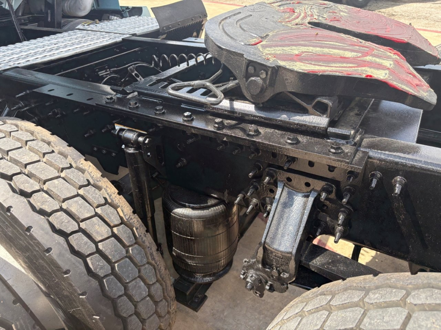 Volvo VNL64T760 truck chassis showing undercarriage components including air tank, rear suspension, and fifth wheel with red wear cover.