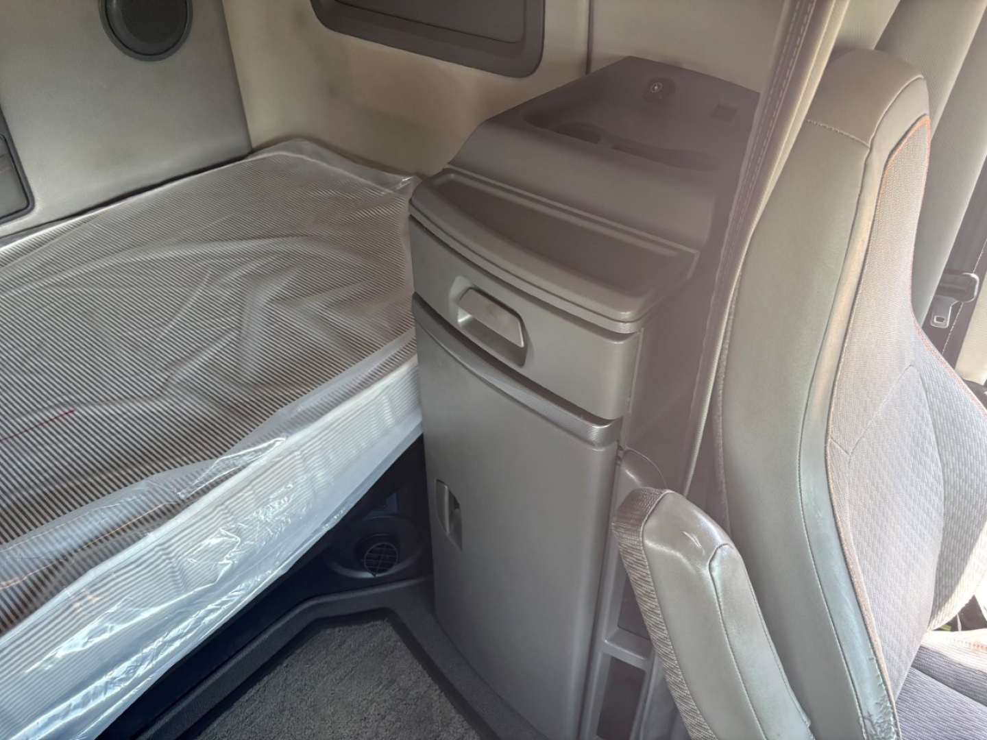 Volvo VNL64T760 sleeper cab interior showing bed area and storage compartments with fabric seat and console panel.