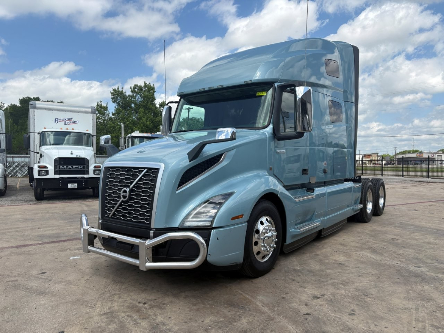 Volvo VNL64T760 semi truck in light blue, front-three-quarter view, with chrome bumper guards and grille; sleeper cab with tall roof and dual rear axles.