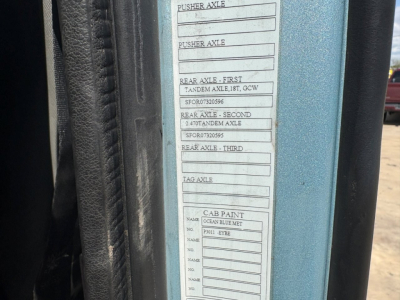 Truck door jamb label showing axle specifications and cab paint Ocean Blue Met, plus wheel/tire tag areas.