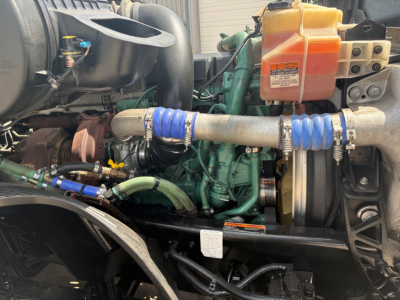 Volvo VNL64T760 engine bay showing coolant reservoir, hoses, belts, and radiator with hoses and clamps.