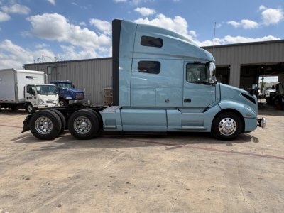 21st century Volvo VNL64T760 semi-truck tractor in blue, side view showing sleeper cab and dual rear axles.