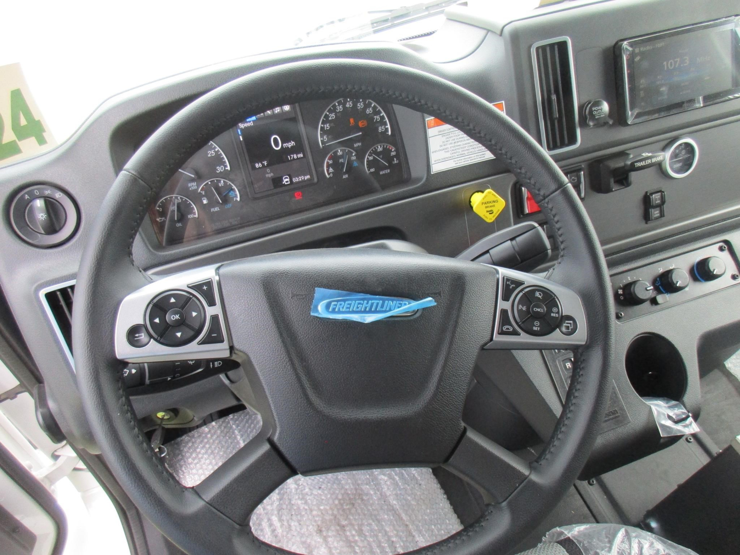 Steering wheel and instrument cluster of a Freightliner M2 106 truck cabin showing dashboard gauges and center console.