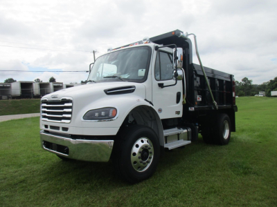 Freightliner M2 106 dump truck in white cab with black dumping bed, front three-quarter view showing chrome grille, headlights, and right-side steps.