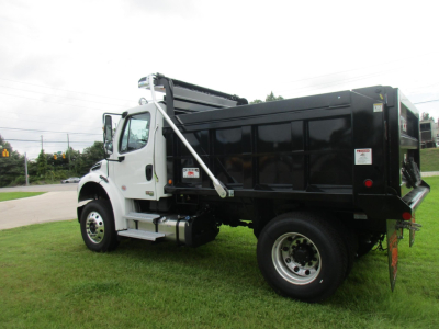 Dump truck body on Freightliner M2 106 with black dump bed and white cab, side view showing steps and front wheel.