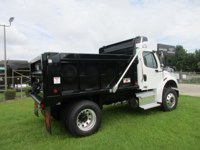 Freightliner M2 106 dump truck side rear view showing black dump bed and white cab with chrome steps