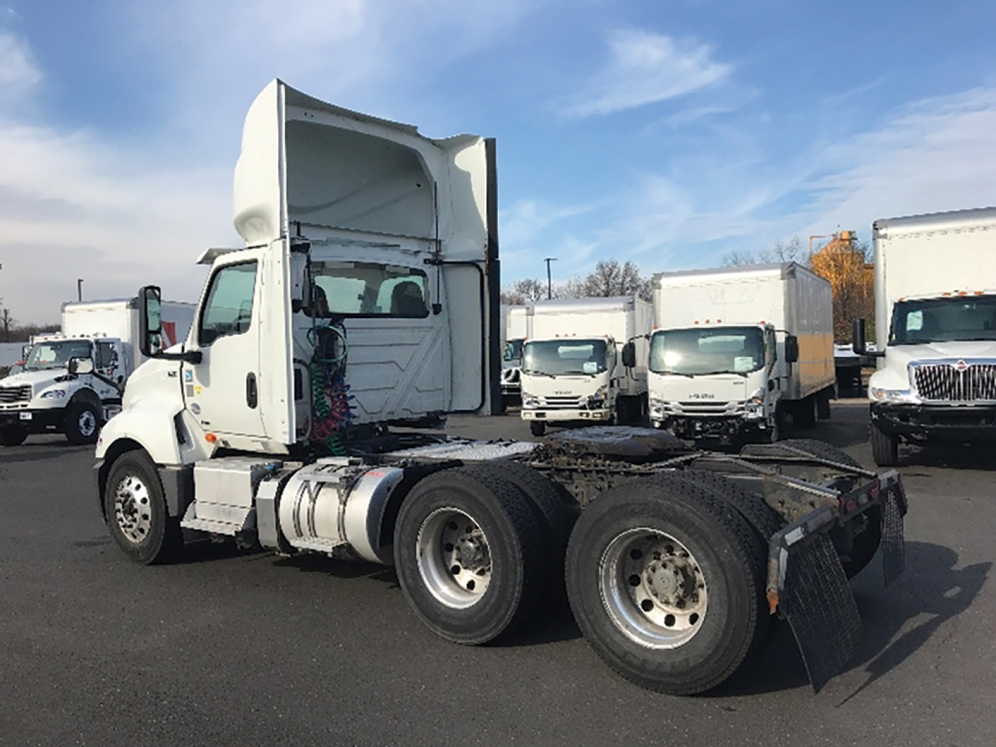 Truck chassis of a 2020 International LT625 tractor in a used trucks lot, cab tilted up showing rear wheels and fifth wheel attachment.