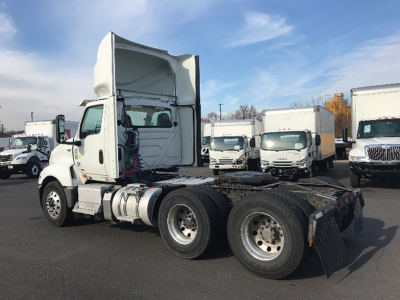 Truck chassis of a 2020 International LT625 tractor in a used trucks lot, cab tilted up showing rear wheels and fifth wheel attachment.