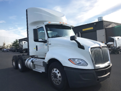 International LT625 conventional daycab truck in white, front three-quarter view showing cab, fuel tanks, and dual rear axles.