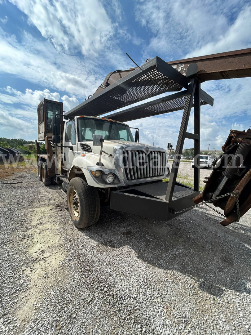 Truck with grapple attachment in front view showing heavy equipment truck used 2008 International 74400BA with crane/boom and metal rack on front.