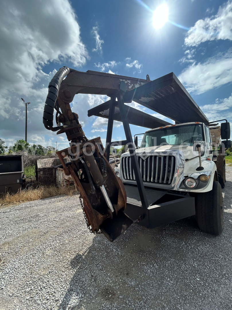 Heavy-duty International truck with a front-mounted grapple attachment for a grapple truck, hydraulic hoses coiled above the arm, cab with grille and headlights visible.