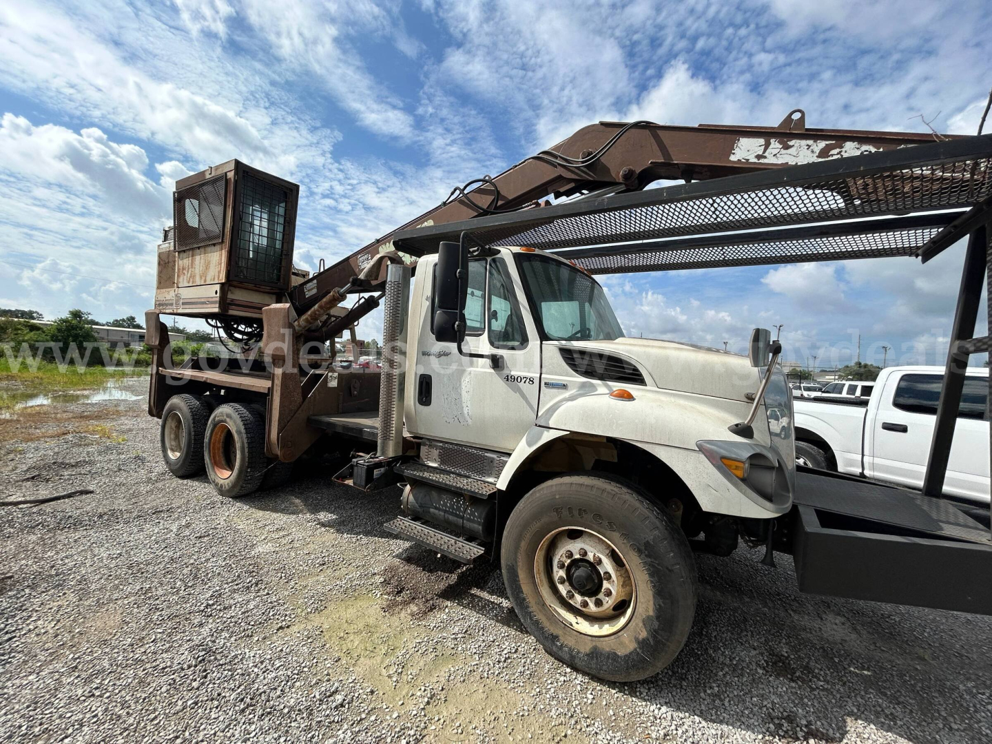 International 74400BA grapple truck showing attached grapple arm and loading bed with cab side and wheels visible.