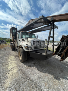 Truck with grapple attachment in front view showing heavy equipment truck used 2008 International 74400BA with crane/boom and metal rack on front.