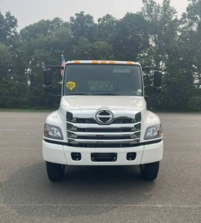 Front view of a white 2027 Hino L6 cab chassis truck with grille, headlights, and Hino emblem visible.