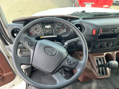 Cab interior of a 2027 Hino L6 truck showing steering wheel, instrument cluster, center console, and gear selector.