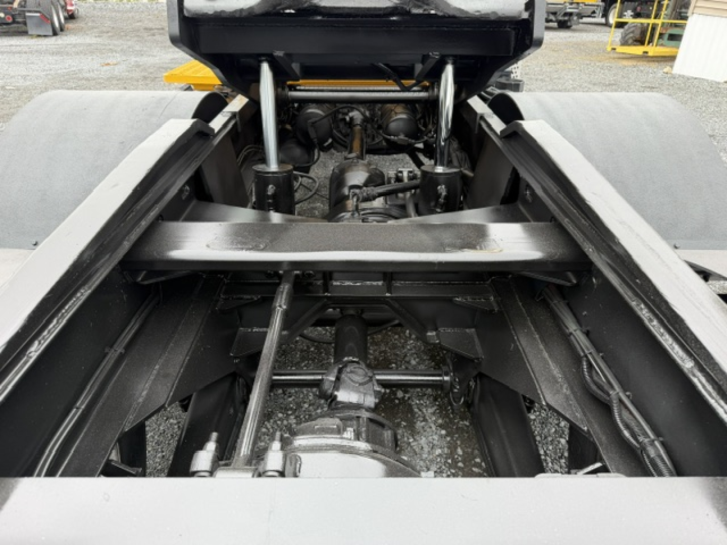 Truck chassis view showing undercarriage, suspension, and drive shaft with hydraulic components.